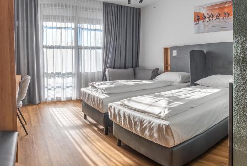 a hotel room with two beds and a window at Sportschule Oberhaching in Oberhaching