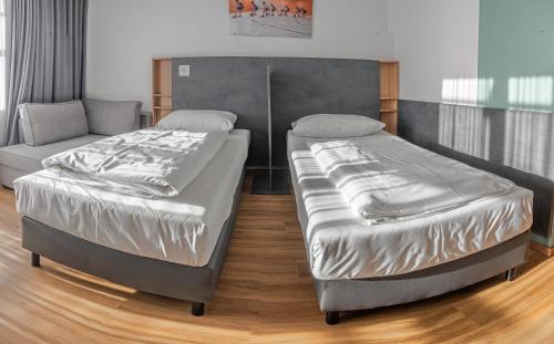 two beds and a couch in a room at Sportschule Oberhaching in Oberhaching