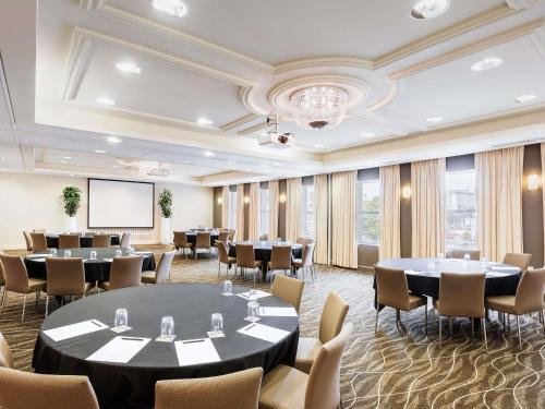a conference room with tables and chairs and a projection screen at Novotel Christchurch Cathedral Square in Christchurch