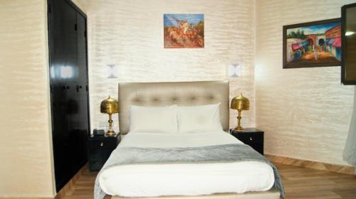 a bedroom with a bed with two night stands and two lamps at Hotel Nouzha in Fès
