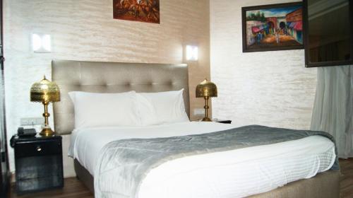 a bedroom with a large white bed with two lamps at Hotel Nouzha in Fès