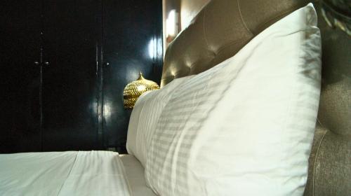 a bed with white pillows and a brown head board at Hotel Nouzha in Fès