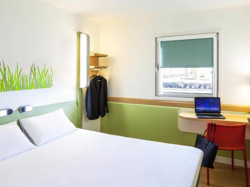 a bedroom with a bed and a laptop on a desk at ibis budget Leicester in Leicester