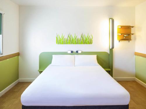 a large white bed in a room with green accents at ibis budget Leicester in Leicester