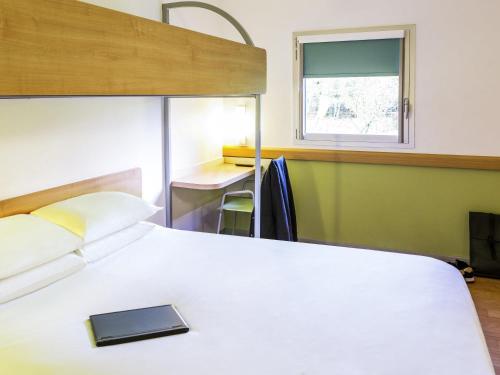 a bedroom with a bed and a desk and a window at ibis budget Derby in Derby
