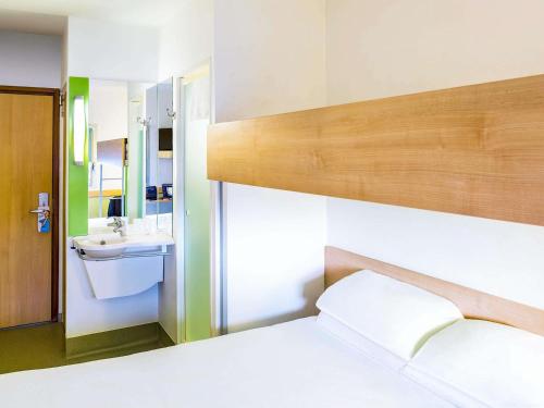 a bathroom with a bed and a sink and a mirror at ibis budget Derby in Derby