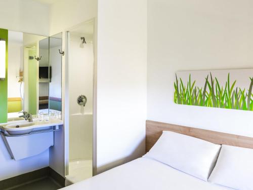 a bedroom with a bed and a sink and a mirror at ibis budget Derby in Derby