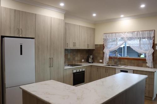 een keuken met houten kasten en een wit aanrecht bij Black Rock Cottage in Camperdown