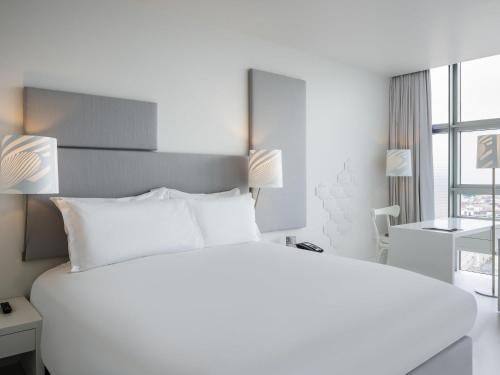 a white bedroom with a large bed and a desk at SO/ Vienna in Vienna