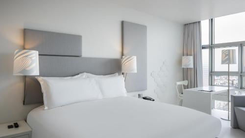 a white bedroom with a large bed and a desk at SO/ Vienna in Vienna