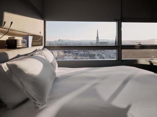 a bedroom with a white bed and a large window at SO/ Vienna in Vienna