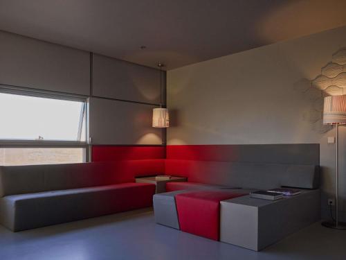 a living room with a couch and a red accent wall at SO/ Vienna in Vienna