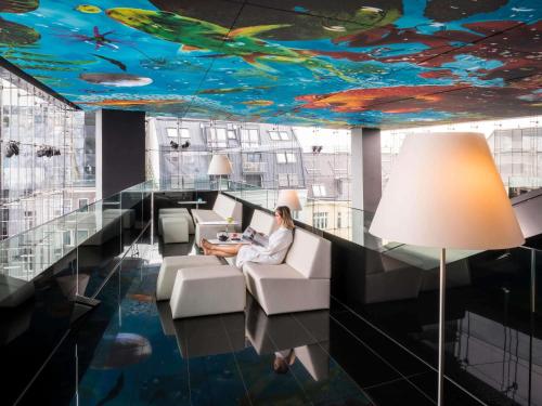 a woman sitting in a chair in a room with a ceiling covered inpired at SO/ Vienna in Vienna