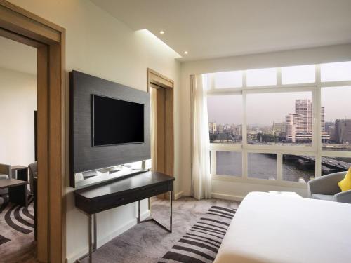 a hotel room with a bed and a flat screen tv at Novotel Cairo El Borg in Cairo