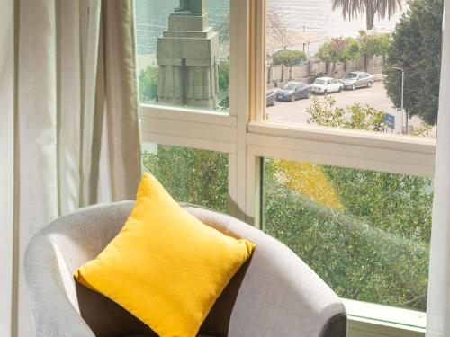 a yellow pillow sitting in a chair in front of a window at Novotel Cairo El Borg in Cairo