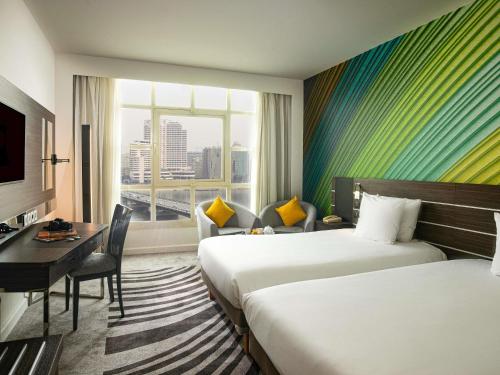 a hotel room with two beds and a desk and a window at Novotel Cairo El Borg in Cairo