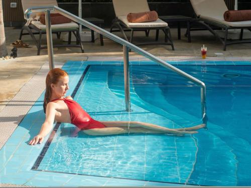 a woman laying on the side of a swimming pool at Novotel Cairo El Borg in Cairo