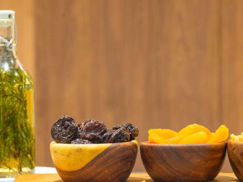 three wooden bowls filled with fruit and a bottle of oil at Novotel Cairo El Borg in Cairo