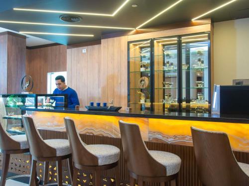 a man standing at a bar in a restaurant at Novotel Cairo El Borg in Cairo