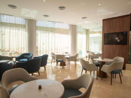 a waiting room with tables and chairs and windows at Novotel Cairo El Borg in Cairo