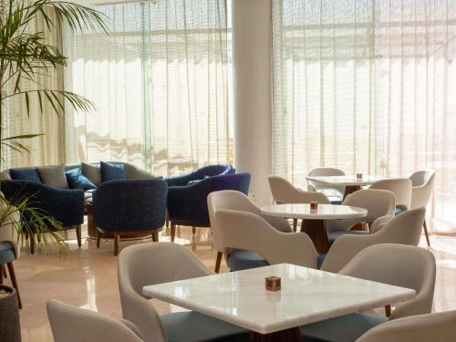 a waiting room with tables and chairs and windows at Novotel Cairo El Borg in Cairo