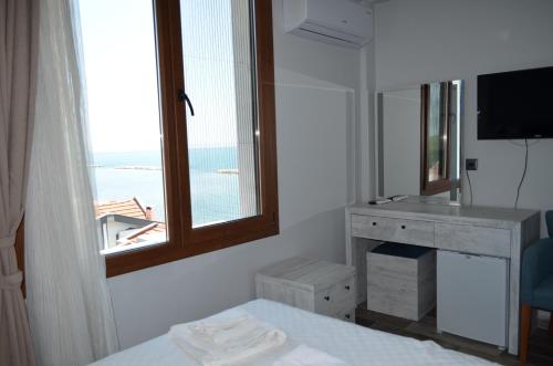a room with a window and a desk with a mirror at Özen Otel in Ayvalık