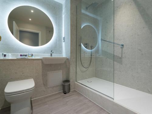 a bathroom with a toilet and a shower and a mirror at Mercure Blackburn Dunkenhalgh Hotel & Spa in Blackburn