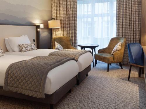 a hotel room with a bed and a desk and chairs at Mercure Blackburn Dunkenhalgh Hotel & Spa in Blackburn