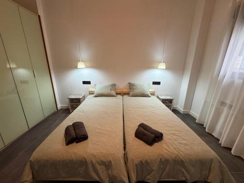a bedroom with a large bed with two slippers on it at Las Arcas, cómodo apartamento cerca del centro in Valladolid