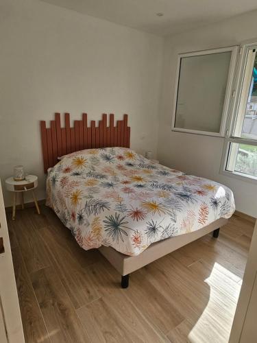 Appartement entouré de verdure في Saint-Martin-de-Seignanx: غرفة نوم بها سرير مع لحاف عليه