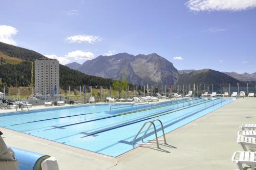 a large swimming pool with mountains in the background at Shackleton Chalet in Sestriere