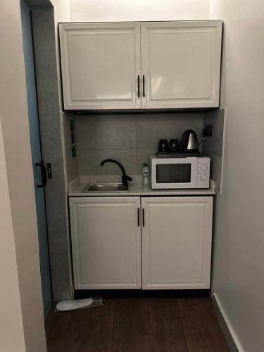 a small kitchen with white cabinets and a microwave at A studio in Al-Murouj self check in in Riyadh