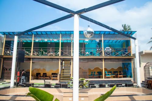 a building with a blue roof with tables and chairs at Xcape Beach Club in Cape Coast