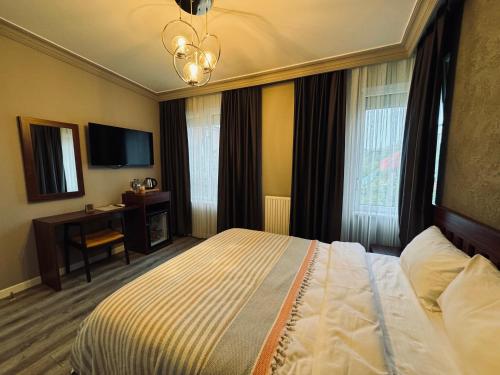 a hotel room with a bed and a desk and windows at Treekos Suite Hotel Istanbul Airport in Arnavutköy