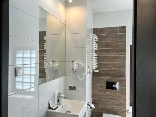 un bagno bianco con lavandino e specchio di REST HOTEL VARIA Działdowo a Działdowo