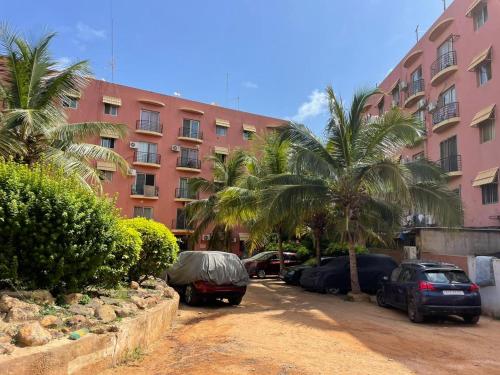 达喀尔Harmony residence dakar的一栋粉色大楼前的停车场