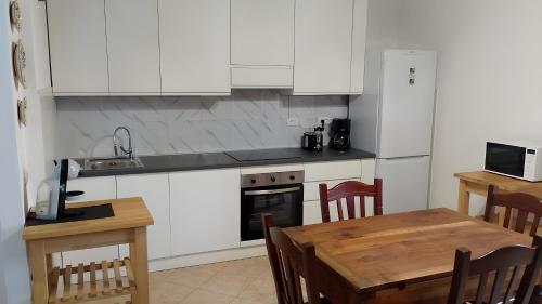 コッレ・ディ・ヴァル・デルザにあるZia Leleの白いキャビネットと木製のテーブルのあるキッチン