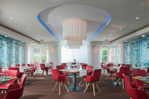 a dining room with tables and chairs and a chandelier at Mintrops Land Hotel Burgaltendorf in Essen