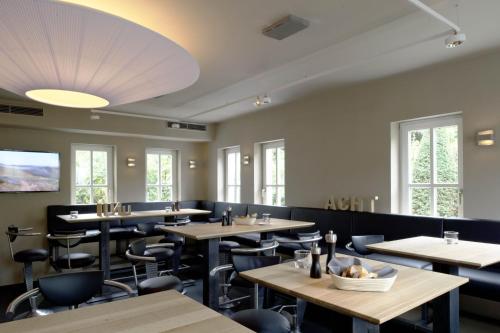 a dining room with tables and chairs and windows at Mintrops Land Hotel Burgaltendorf in Essen