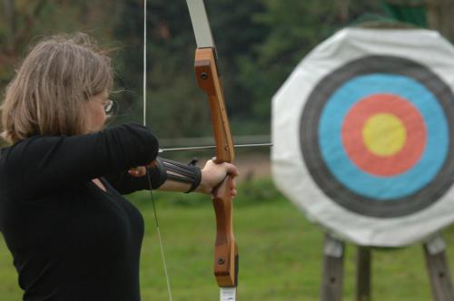a woman holding a bow and arrow in front of a target at Mintrops Land Hotel Burgaltendorf in Essen