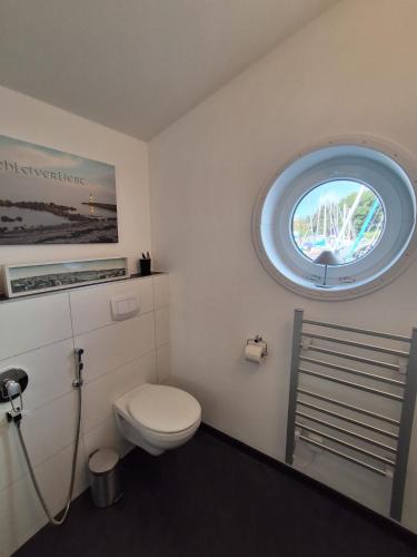 a bathroom with a toilet and a round window at Schleiverliebt 52 in Schleswig