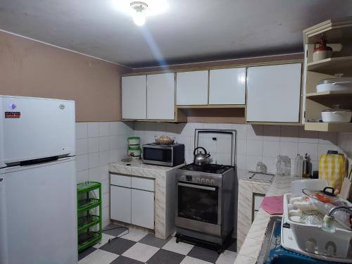 a kitchen with white cabinets and a stove and refrigerator at Dpto Amplio, TV75in, Cochera, Céntrico y BBQ in Huancayo