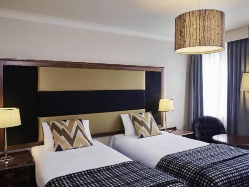 a hotel room with two beds and a table at Mercure Exeter Southgate Hotel in Exeter