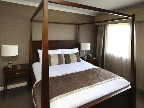 a bedroom with a canopy bed and a window at Mercure Exeter Southgate Hotel in Exeter