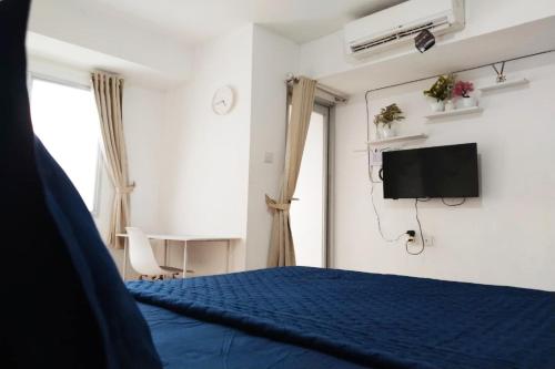 a bedroom with a blue bed and a tv at Antareja LoftVilles By Reccoma in Dukuh