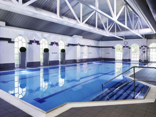 a large swimming pool with blue water in a building at Mercure Exeter Southgate Hotel in Exeter