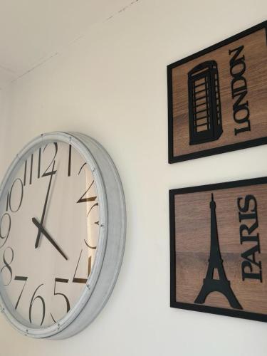 a clock on a wall next to two pictures at San Benito B&B cerca Quito Aeropuerto - Tumbaco in Tumbaco