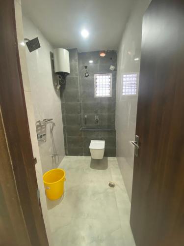a bathroom with a toilet and a yellow bucket at People Leaf Homestay in Gaya