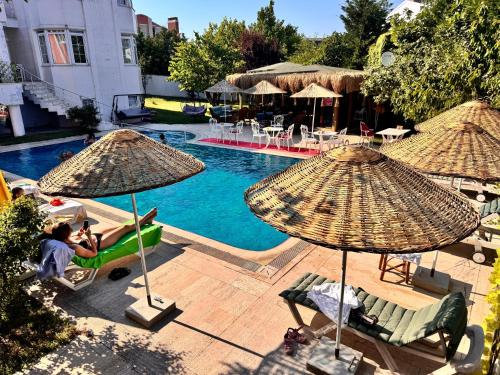 a pool with umbrellas and people sitting in chairs next to it at Treekos Suite Hotel Istanbul Airport in Arnavutköy