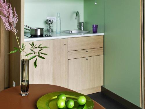 a kitchen with a table with a plate of fruit on it at Aparthotel Adagio Bordeaux Centre Gambetta in Bordeaux
